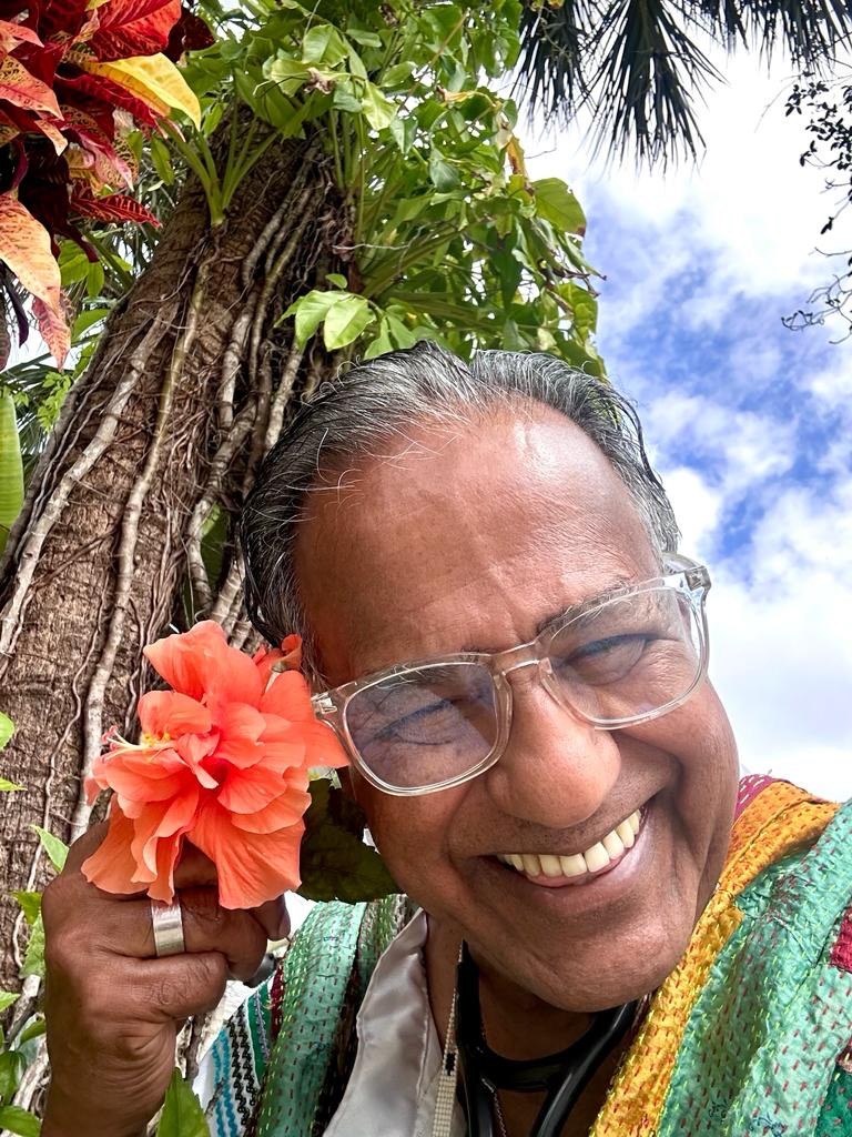 The Physician Anthropologist smiling with an orange flower in a tropical garden