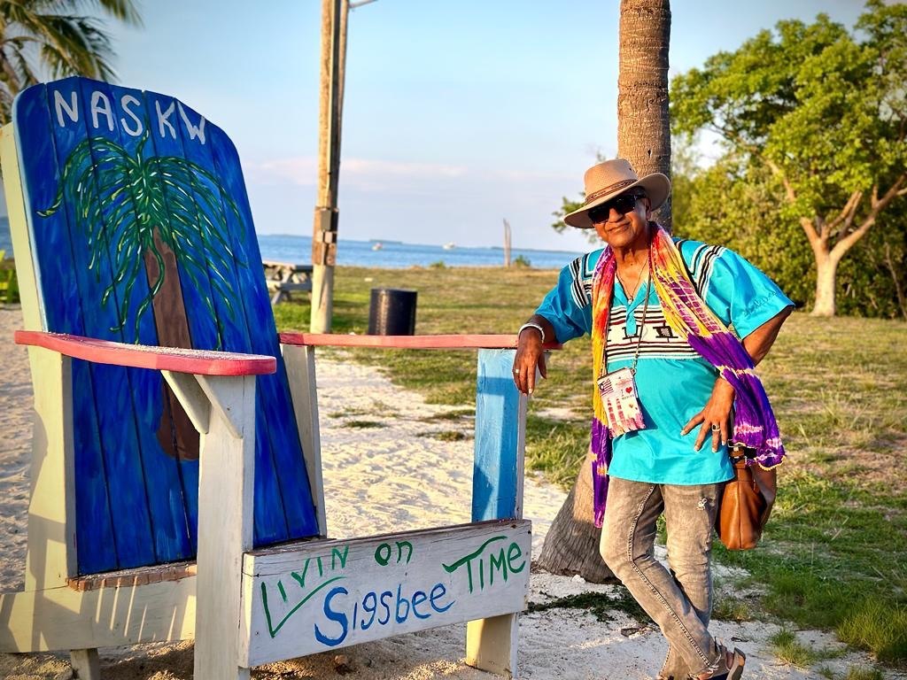 The Physician Anthropologist standing beside a colorful coastal chair and sign